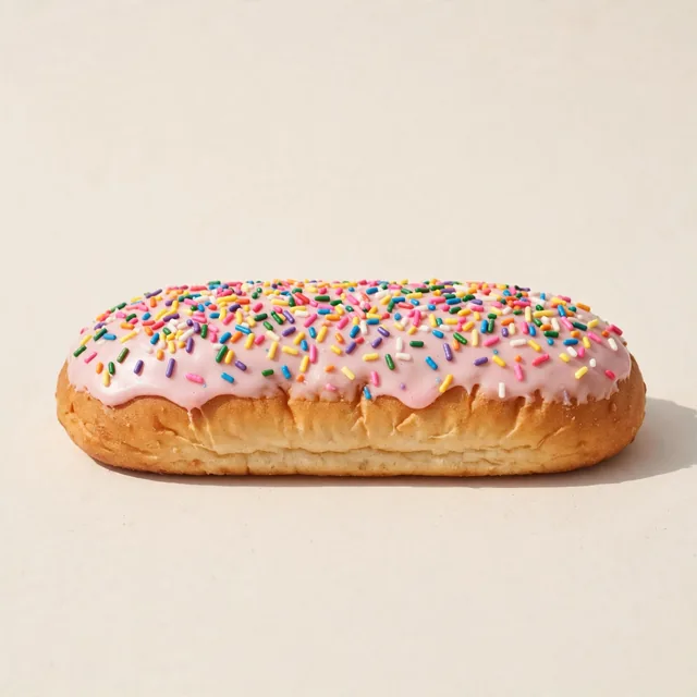 A finger bun with pink icing and sprinkles